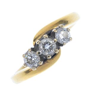 An 18ct gold diamond three-stone ring. The brilliant-cut diamonds, to the asymmetric shoulders. Esti