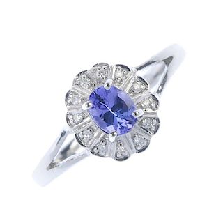 A 9ct gold tanzanite and diamond floral cluster ring. The oval-shape tanzanite within a single-cut d