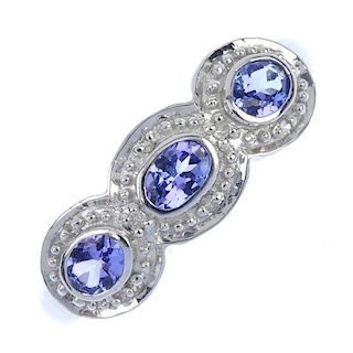 A 9ct gold tanzanite and diamond three-stone ring. The oval-shape tanzanite collet line, each within