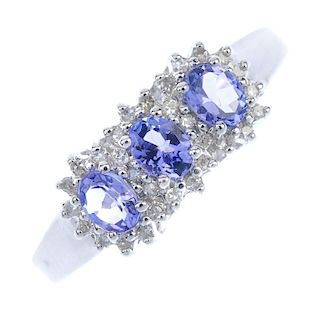 A 9ct gold tanzanite and diamond triple cluster ring. The oval-shape tanzanite line, within a single