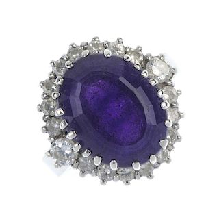 An amethyst and diamond cluster ring. The oval-shape amethyst, within a brilliant-cut diamond surrou