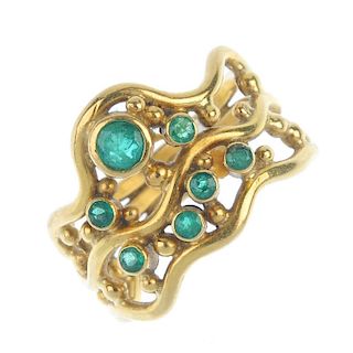 A 1970s 18ct gold emerald dress ring. Designed as three convergent scrolling lines, with vari-size c