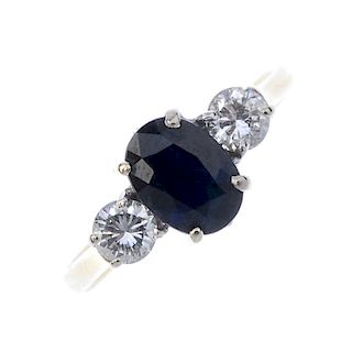 An 18ct gold sapphire and diamond three-stone ring. The oval-shape sapphire, with brilliant-cut diam