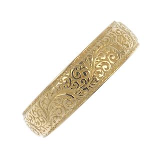 A late Victorian 18ct gold band ring. The scroll engraved band, with textured border. Hallmarks for