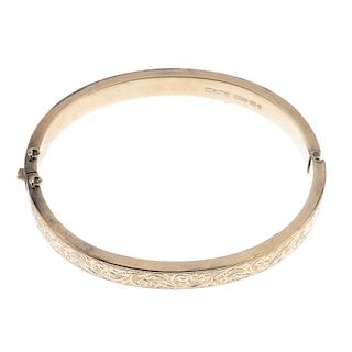 A late Victorian 9ct gold hinged bangle. Designed an a scrolling foliate hinged bangle, with safety
