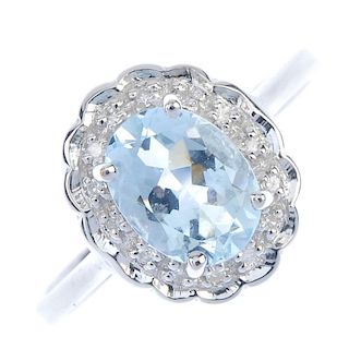 A 9ct gold aquamarine and diamond cluster ring. The oval-shape aquamarine, within an illusion-set si
