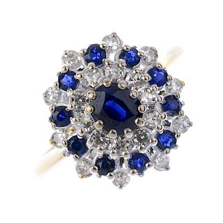 An 18ct gold sapphire and diamond cluster ring. The oval-shape sapphire, within an alternating singl