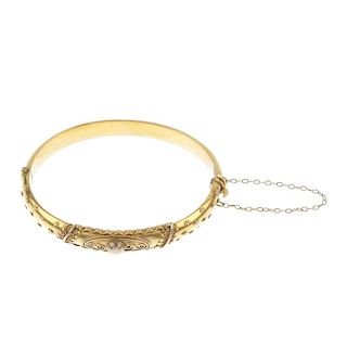 A late Victorian gold hinged bangle. The cannetille kite-shape scalloped panel, with bead motif side