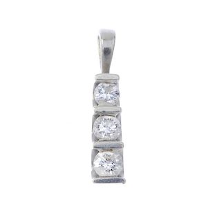 A 9ct gold diamond three-stone pendant. The graduated brilliant-cut diamond line, with bar spacers,