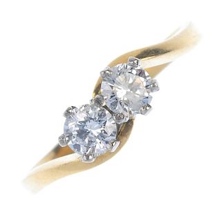 A diamond crossover ring. The twin brilliant-cut diamonds, to the asymmetric shoulders and plain ban