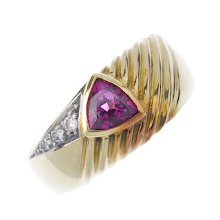 A garnet and diamond dress ring. The triangular-shape garnet collet, to the grooved panel and brilli