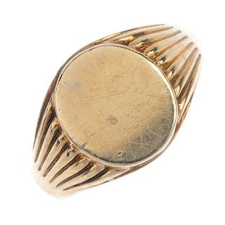 A mid 20th century 9ct gold signet ring. The oval-shape polished panel, to the grooved shoulders and