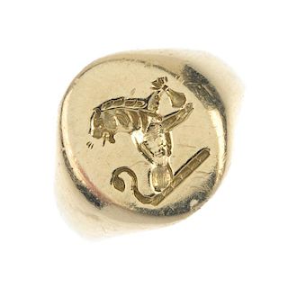 An 18ct gold signet ring. The oval-shape panel, engraved to depict a crest of a lion holding a sack,