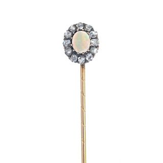 An opal and diamond stickpin. The oval opal cabochon, within a rose-cut diamond surround, to the pla