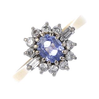 (57887) An 18ct gold sapphire and diamond cluster ring. The oval sapphire within a brilliant-cut dia