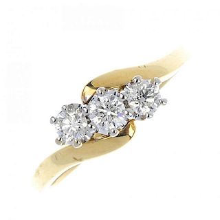 An 18ct gold diamond three-stone ring. Of crossover design, the brilliant-cut diamond diagonal line,