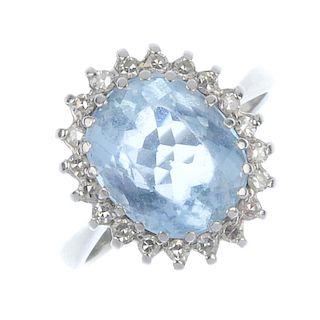 An aquamarine and diamond cluster ring. The oval-shape aquamarine, within a single-cut diamond surro