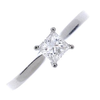A platinum diamond single-stone ring. The square-shape diamond, to the tapered shoulders and plain b