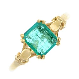 An 18ct gold emerald single-stone ring. The rectangular-shape emerald, to the stylised foliate shoul
