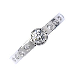 A platinum diamond ring. The brilliant-cut diamond collet, to the similarly-cut diamond line sides,