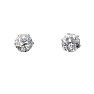 A pair of diamond single-stone ear studs. Each set with an old-cut diamond, weighing 1.22 and 1.31ct