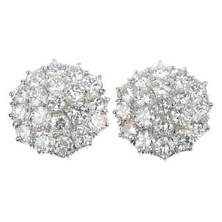 A pair of diamond cluster ear studs. Each designed as a brilliant-cut diamond, within a brilliant-cu
