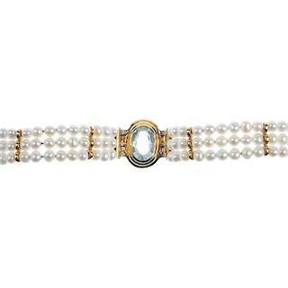 <p>A topaz, diamond and cultured pearl bracelet. The oval-shape blue topaz, within a grooved surroun