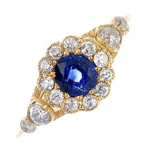 A sapphire and diamond cluster ring. The circular-shape sapphire, within an old-cut diamond surround