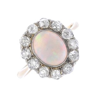 An opal and diamond ring. The circular opal cabochon, within an old-cut diamond surround, to the tap