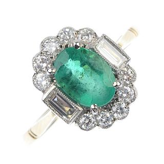An emerald and diamond cluster ring. The oval-shape emerald, to the baguette-cut diamond sides, with