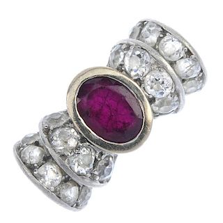 A ruby and diamond dress ring. Designed as a stylised bow, the oval-shape ruby collet centre, with o