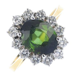 An 18ct gold tourmaline and diamond cluster ring. The oval-shape tourmaline, within a brilliant-cut