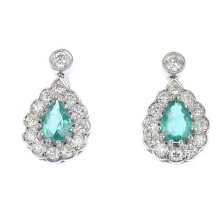 A pair of emerald and diamond ear pendants. Each designed as a pear-shape emerald, within a brillian