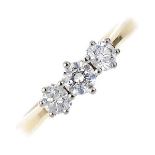 An 18ct gold diamond three-stone ring. The graduated brilliant-cut diamond line, to the tapered shou