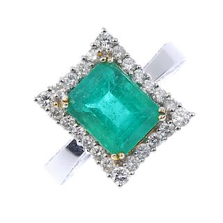 An emerald and diamond cluster ring. The rectangular-shape emerald, within a brilliant-cut diamond b