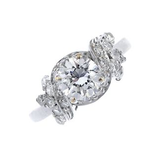 An 18ct gold diamond dress ring. The brilliant-cut diamond, within a single-cut diamond scrolling su