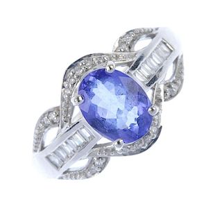 An 18ct gold tanzanite and diamond cluster ring. The oval-shape tanzanite, with baguette-cut diamond
