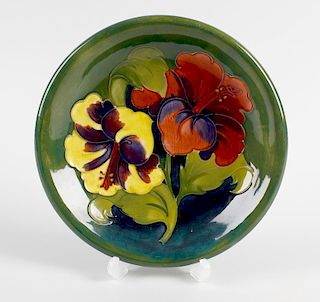 A Walter Moorcroft pottery dish. Decorated in the Hibiscus pattern on glazed green ground, with impr