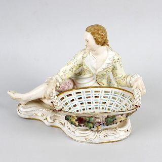 A Bevington porcelain sweetmeat basket. Of Meissen style, modelled as a young male figure wearing fl