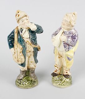 A pair of glazed pottery figures. Each modelled as a male musician carrying a guitar or trumpet and