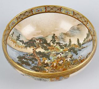 A Japanese Meiji period Satsuma pottery bowl. The interior decorated with figures on a promontory be