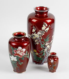 A small group of red-ground cloisonne vases. Comprising a pair of ovoid form decorated with irises a