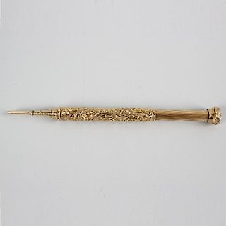 A yellow metal retractable pencil. The barrel decorated with high relief foliate scrollwork and vaca