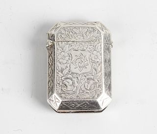 A late Victorian silver vesta case. Of canted oblong form with foliage engraved body, a shield carto