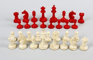 A stained ivory chess set. Comprising natural and red stained sectional pieces, the kings of typical