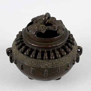 An Oriental bronze koro or incense burner and cover. Of spherical form with pierced domed foliate co
