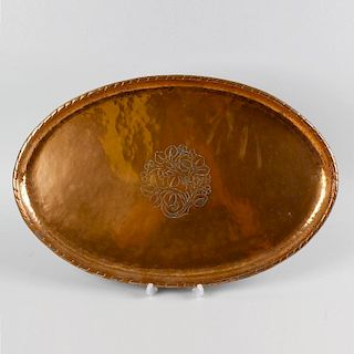 An Arts and Crafts oval copper dish by Hugh Wallis, the central panel, decorated with an engraved de