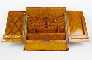 An Edwardian oak stationery cabinet. The sloping fall with twin doors enclosing a shaped interior of