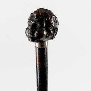 An unusual ebonised walking stick or cane. The handle carved as the head of a child, on engraved met