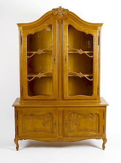 A reproduction oak display cabinet. The upper section with carved scrolled pediment above twin glaze